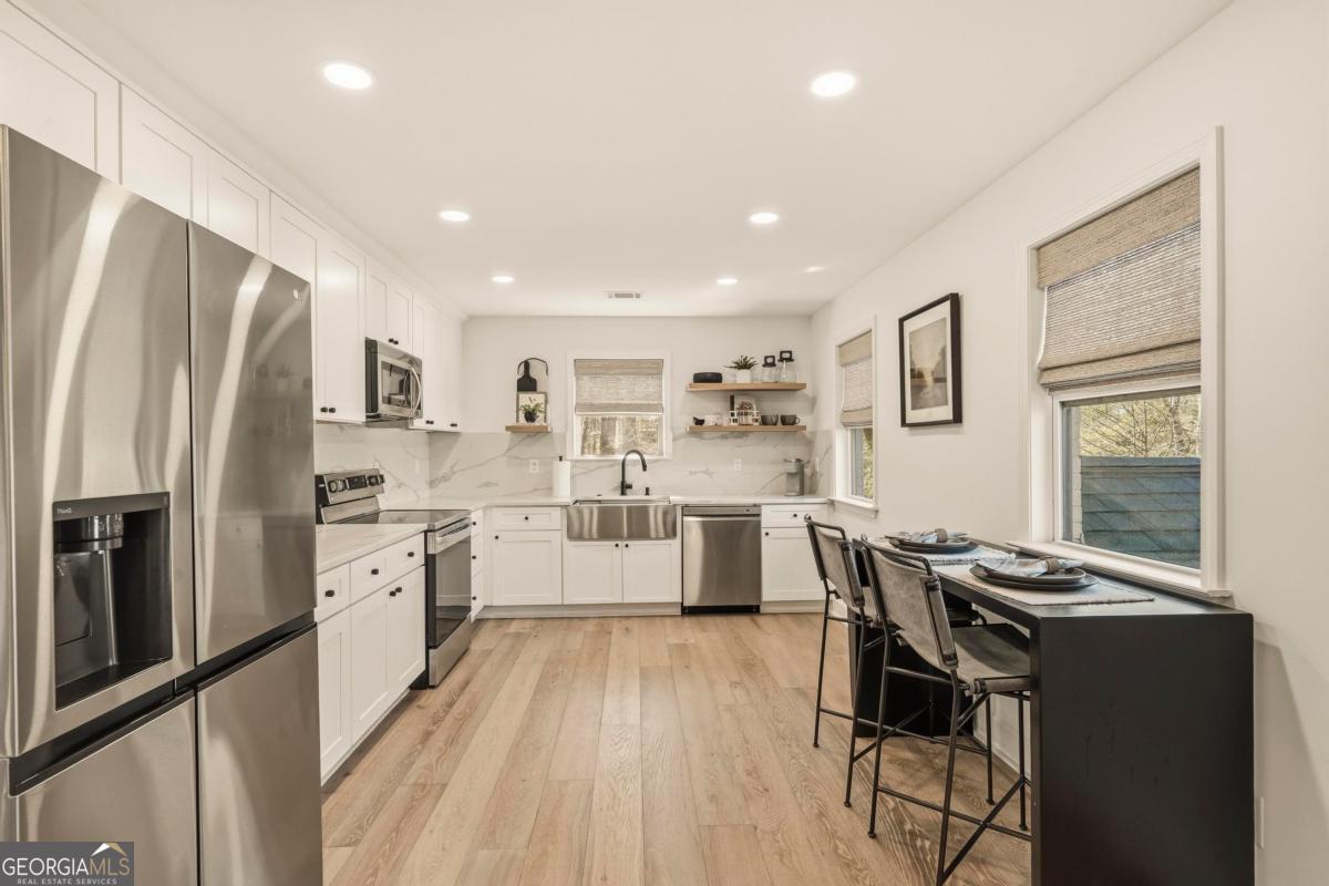 121 Mags Path Eatonton, GA 31024 - Photo 14 of 74 a kitchen with stainless steel appliances a refrigerator a stove a sink dishwasher a dining table and chairs with wooden floor
