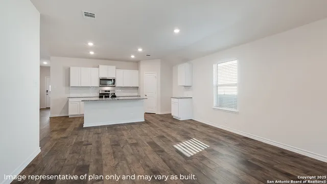 a large kitchen with kitchen island a sink wooden floor and stainless steel appliances