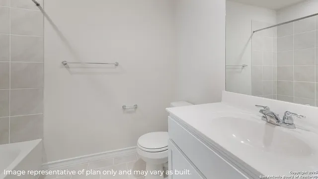 a white toilet sitting next to a white sink and vanity