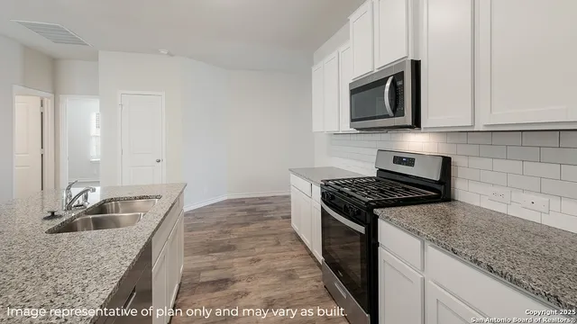 a kitchen with granite countertop a sink stove and microwave
