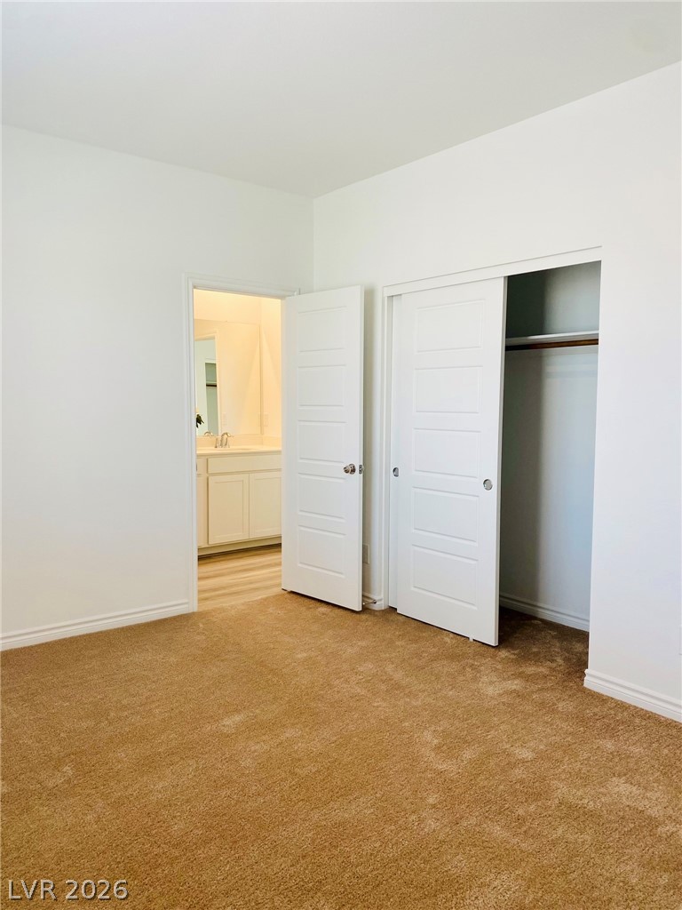 4457 Sawyer Ridge Street Las Vegas, NV 89147 - Photo 21 of 32 This spacious bedroom offers comfortable carpeted flooring and convenient access to a private bathroom.