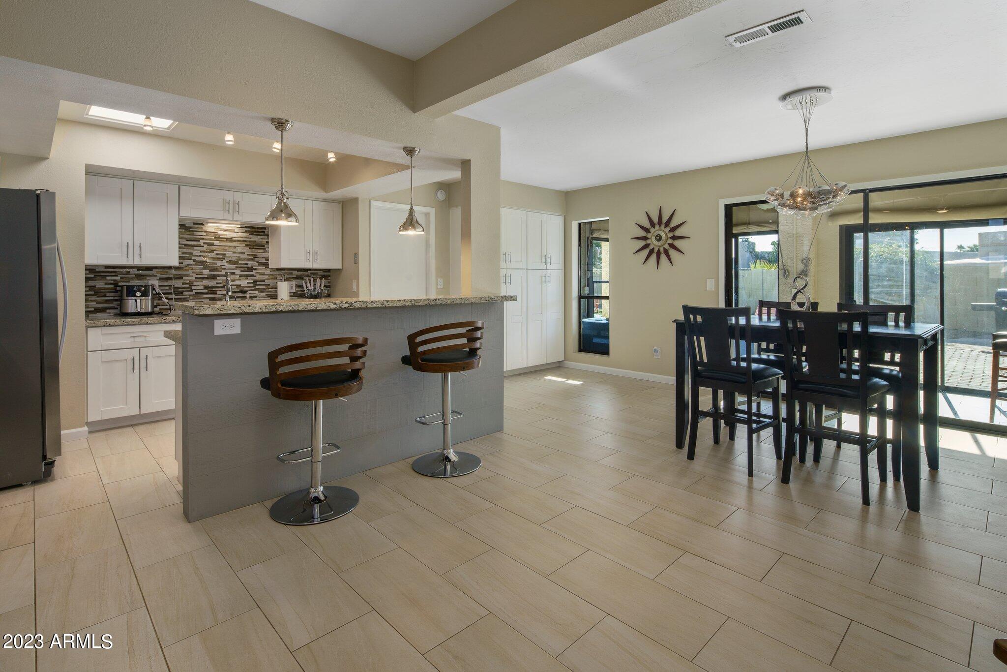 6609 East Phelps Road Scottsdale, AZ 85254 - Photo 10 of 83 a kitchen with stainless steel appliances granite countertop a stove a sink a dining table and chairs with wooden floor
