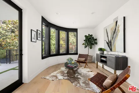 a living room with furniture large window and wooden floor