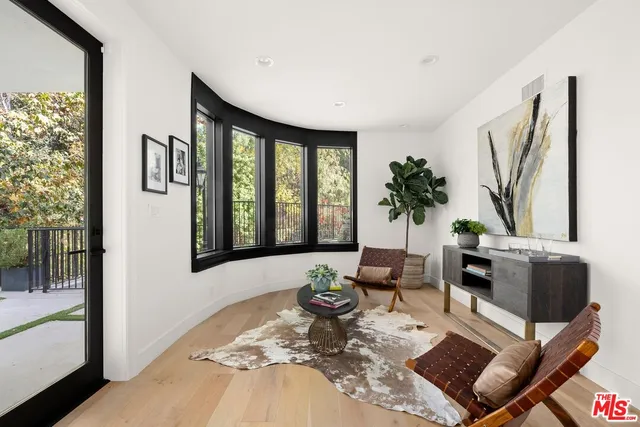 a living room with furniture large window and wooden floor