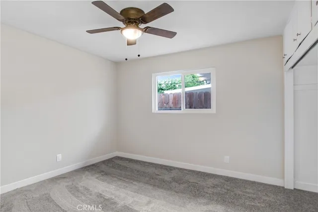 an empty room with a ceiling fan and a window