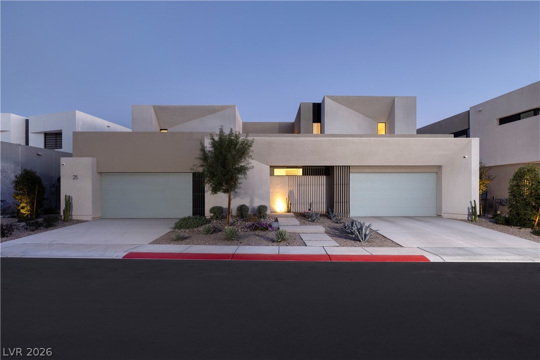 25 Falling Ridge Lane Henderson, NV 89011 - Photo 3 of 48 Modern desert architecture with a welcoming entry, illuminated by subtle landscape lighting.