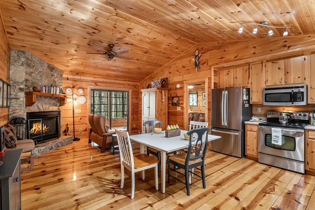 a view of a dining room with furniture a fireplace and wooden floor