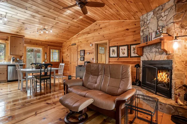 a living room with furniture a fireplace and a dining table with wooden floor
