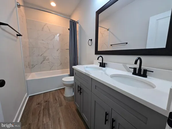 a bathroom with a sink a toilet a mirror and shower