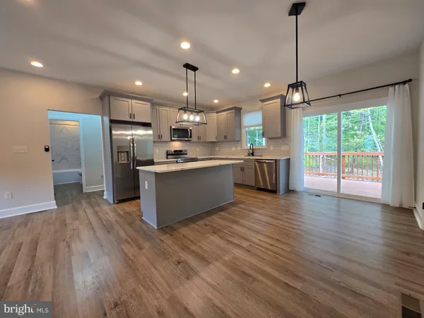 a open kitchen with stainless steel appliances granite countertop a refrigerator a sink dishwasher a stove and white countertops with wooden floor