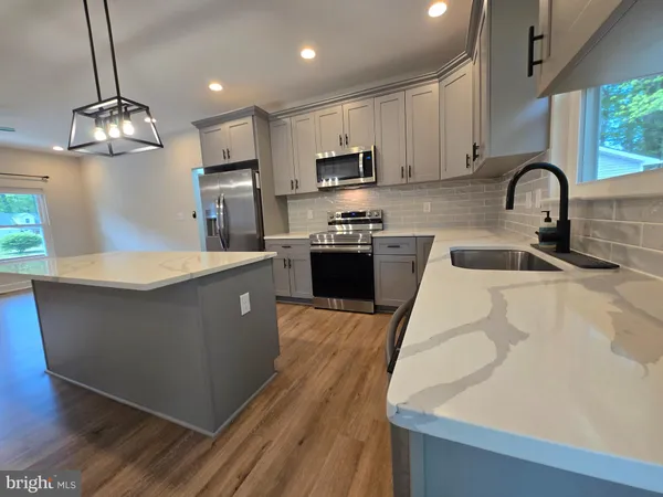 a large kitchen with stainless steel appliances granite countertop a sink a stove and a wooden floors
