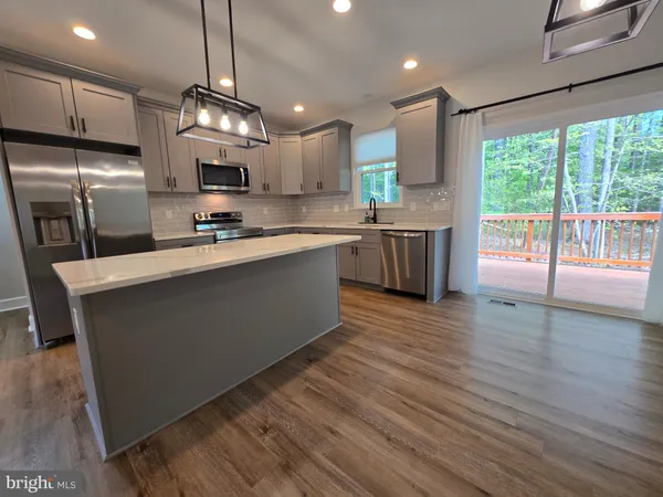 a large kitchen with stainless steel appliances granite countertop a large stove a sink dishwasher and a refrigerator with wooden floor