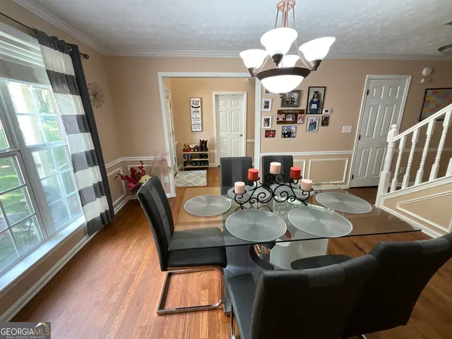 a kitchen with stainless steel appliances granite countertop a stove top oven a refrigerator a dining table and chairs with wooden floor