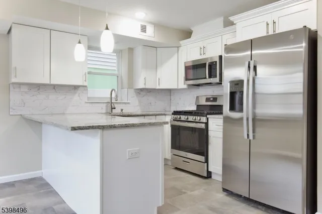 a kitchen with granite countertop a refrigerator a sink a stove a microwave and island