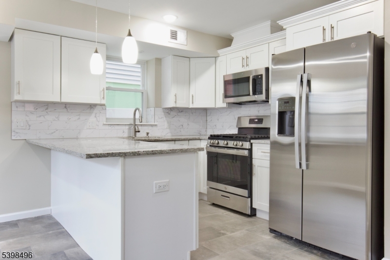 32 Garibaldi Avenue, Unit 1 Newark, NJ 07114 - Photo 2 of 12 a kitchen with granite countertop a refrigerator a sink a stove a microwave and island