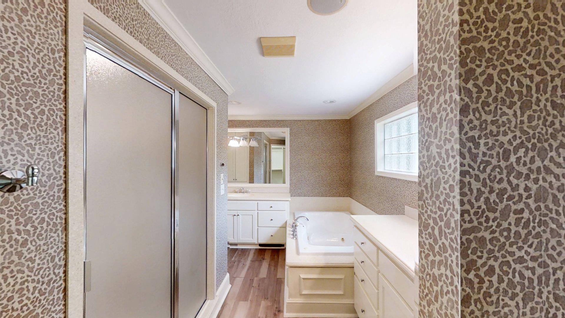 219 F Street Southwest Ardmore, OK 73401 - Photo 44 of 58 Frosted glass shower enclosure, built-in soaking tub, dual vanity with undermount sinks, and wood-finish flooring
