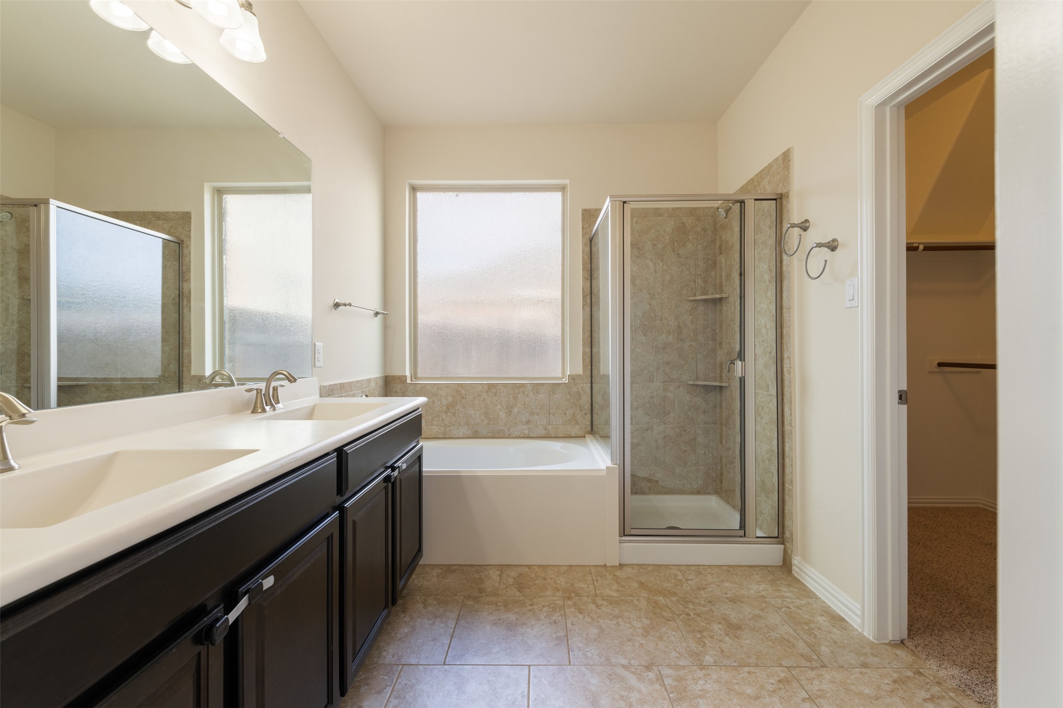 18304 Blush Rose Road Pflugerville, TX 78660 - Photo 11 of 16 Tiled flooring and a double vanity complement the separate shower and tub setup.