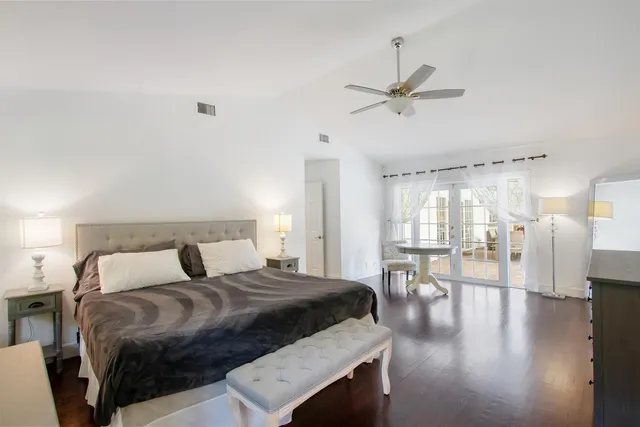a bedroom with a bed a table and chairs with wooden floor