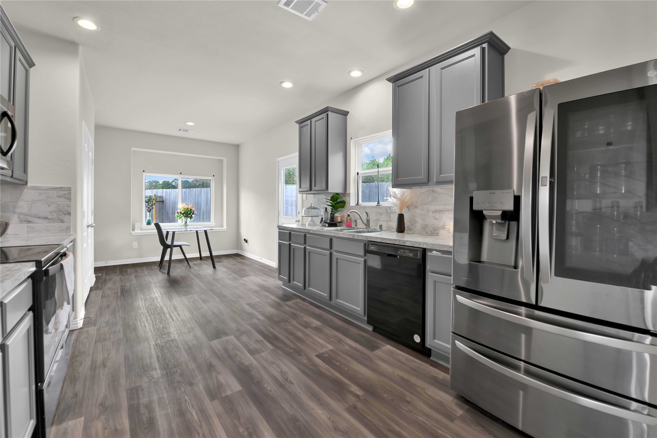 17703 Lion Heart Road Conroe, TX 77306 - Photo 8 of 26 a kitchen with stainless steel appliances a refrigerator a sink dishwasher a stove and white countertops with wooden floor