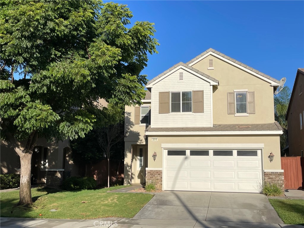a view of a yard in front of a house with a large tree