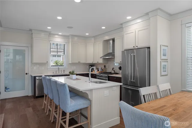 a kitchen with granite countertop a refrigerator a stove a sink a dining table and chairs