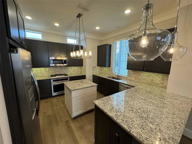 a kitchen with kitchen island a counter top space a sink stainless steel appliances and cabinets