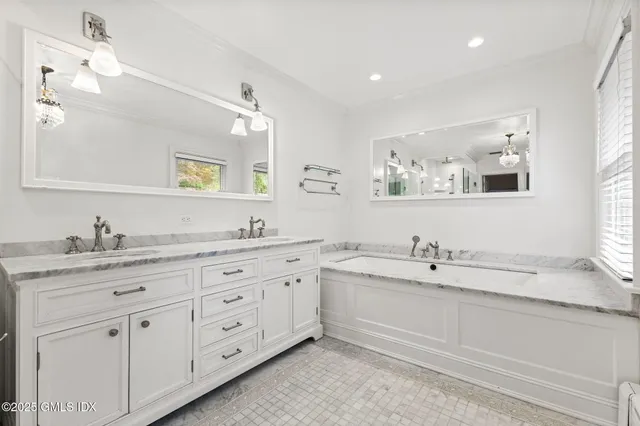 a bathroom with a double vanity sink toilet mirror and bathtub