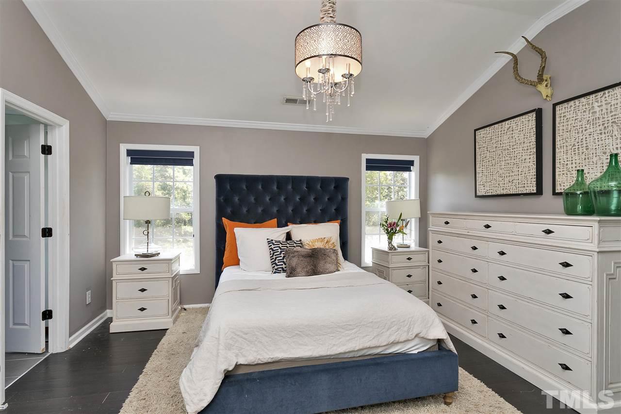 7206 Doverton Court Raleigh, NC 27615 - Photo 12 of 23 a bedroom with a large bed and a chandelier