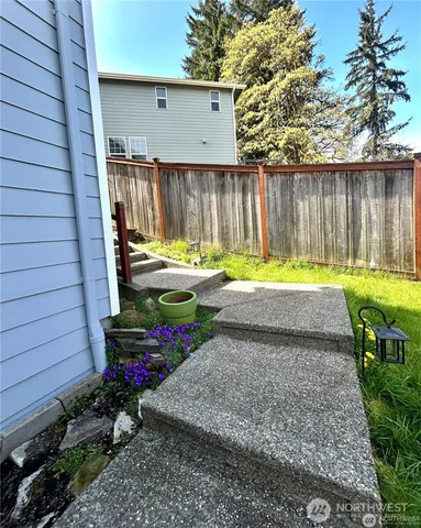 a view of a backyard with chairs potted plants and wooden fence