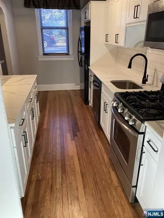 a kitchen with stainless steel appliances granite countertop a stove a sink dishwasher and a refrigerator with wooden floor