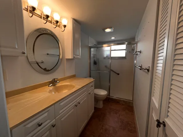 a bathroom with a granite countertop toilet sink and mirror