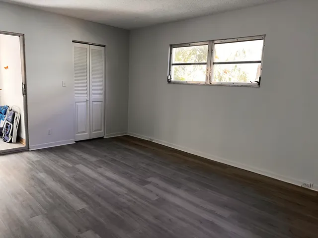 an empty room with wooden floor and windows