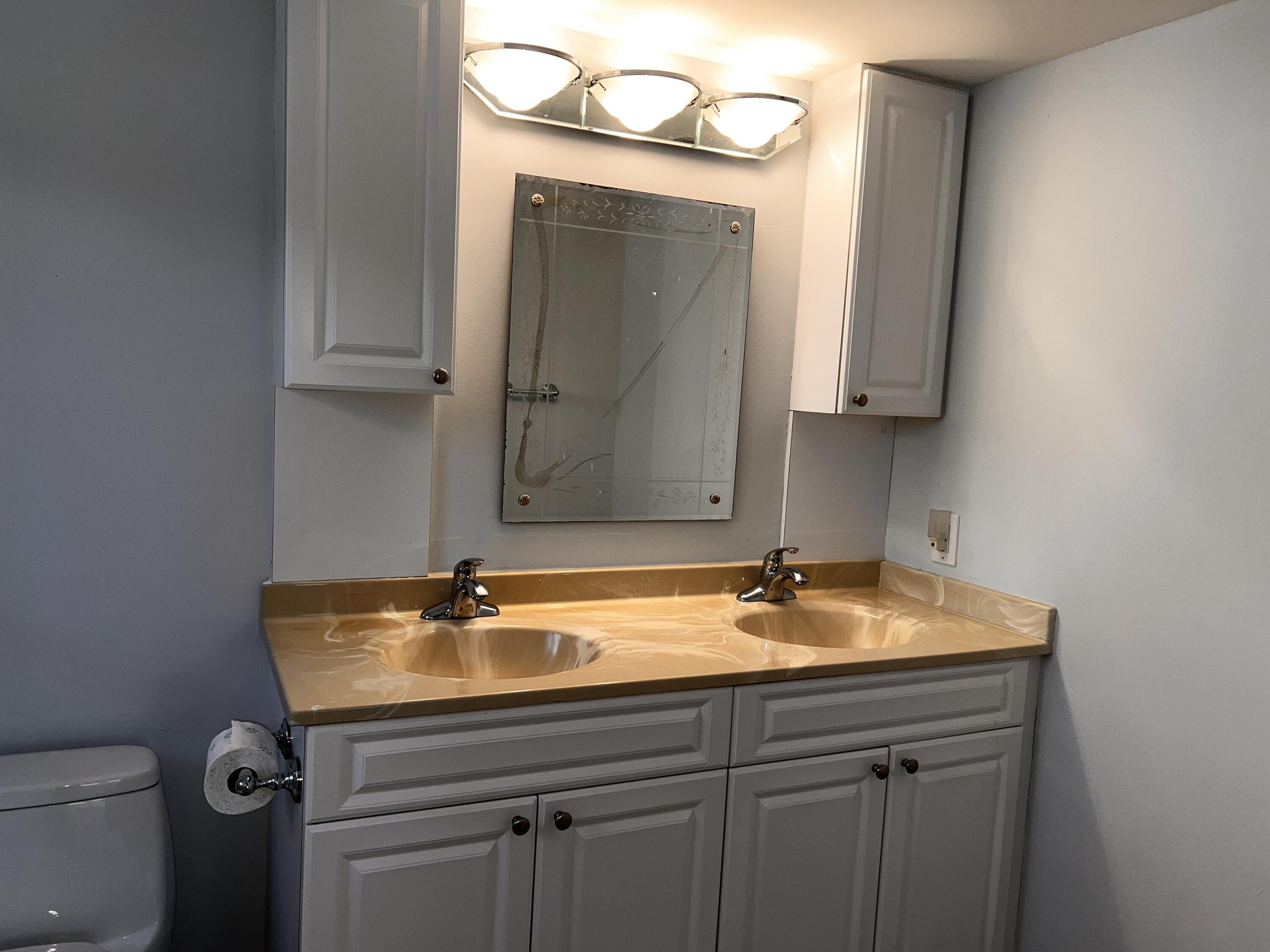 2403 Antigua Circle, Unit O2 Coconut Creek, FL 33066 - Photo 21 of 31 a bathroom with a granite countertop sink a toilet and a mirror
