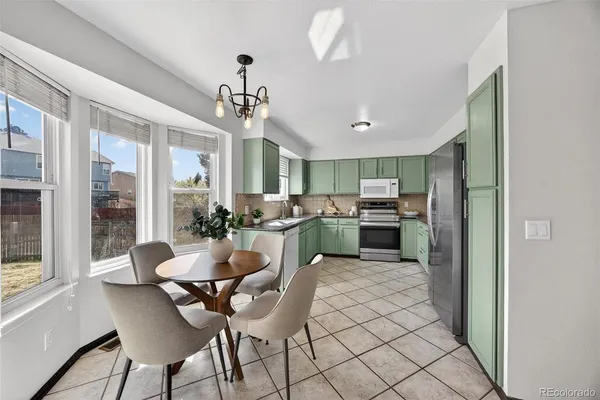 a kitchen with stainless steel appliances kitchen island granite countertop a dining table chairs and a refrigerator