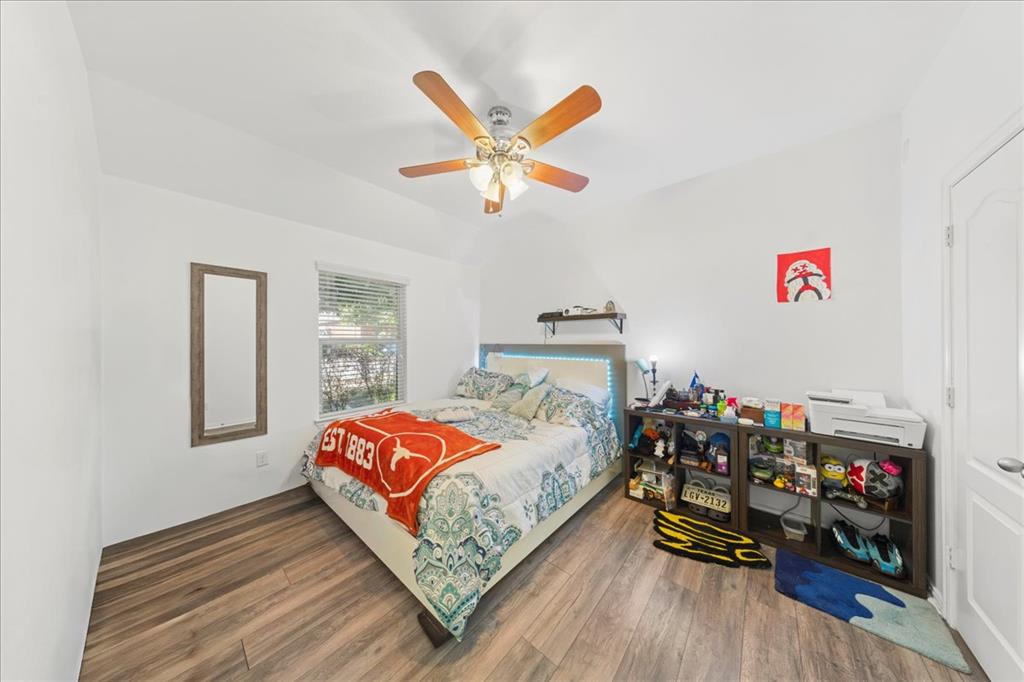 349 Razzmatazz Trail Buda, TX 78610 - Photo 13 of 27 Hardwood-style flooring and a window with blinds define this restful bedroom.