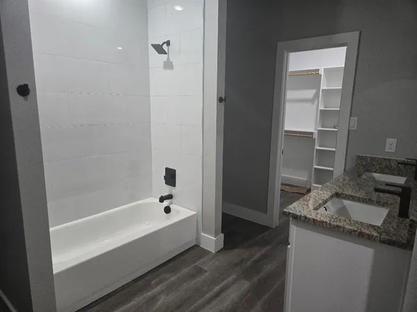 a spacious bathroom with a granite countertop sink and a bathtub