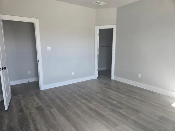 a view of an empty room with wooden floor and closet