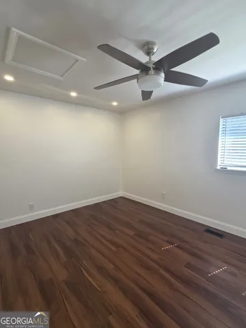 a view of an empty room with wooden floor and a ceiling fan