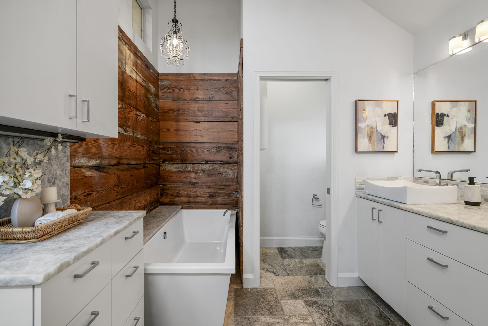 1129 Cedar Pass Road Driftwood, TX 78619 - Photo 22 of 40 This primary bathroom is a total showstopper. You’ve got a deep soaking tub framed by reclaimed wood walls and a crystal chandelier.