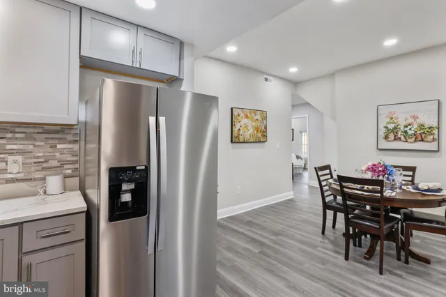 a kitchen with stainless steel appliances a refrigerator a stove a dining table and chairs with wooden floor