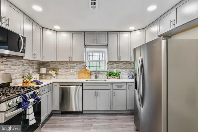 a kitchen with stainless steel appliances a refrigerator a sink and wooden cabinets