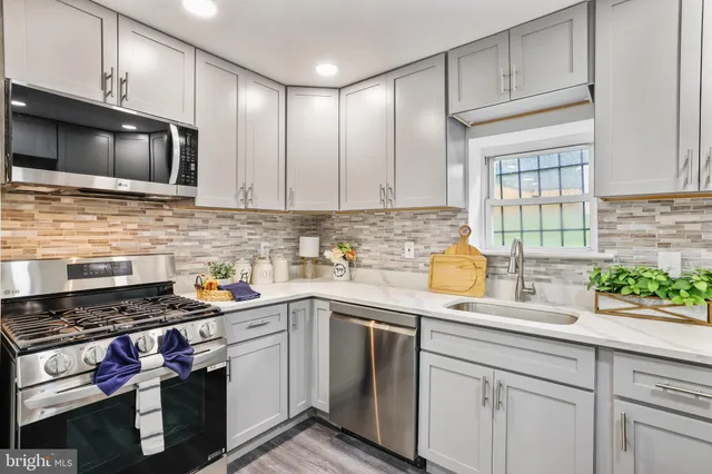 a kitchen with stainless steel appliances a sink a stove cabinets and a window