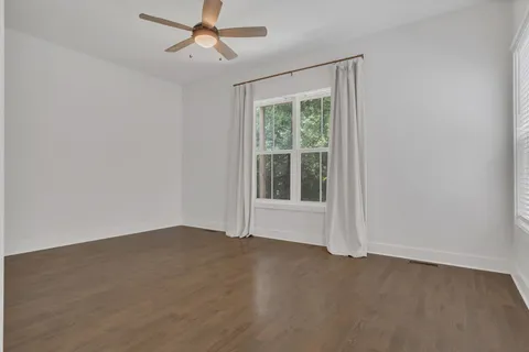 an empty room with a window and ceiling fan