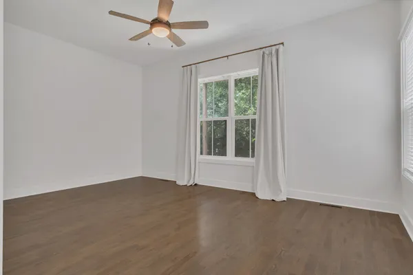 an empty room with a window and ceiling fan