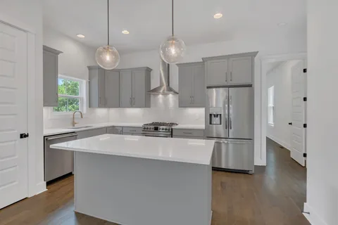 a large kitchen with stainless steel appliances a large center island attached withe living room