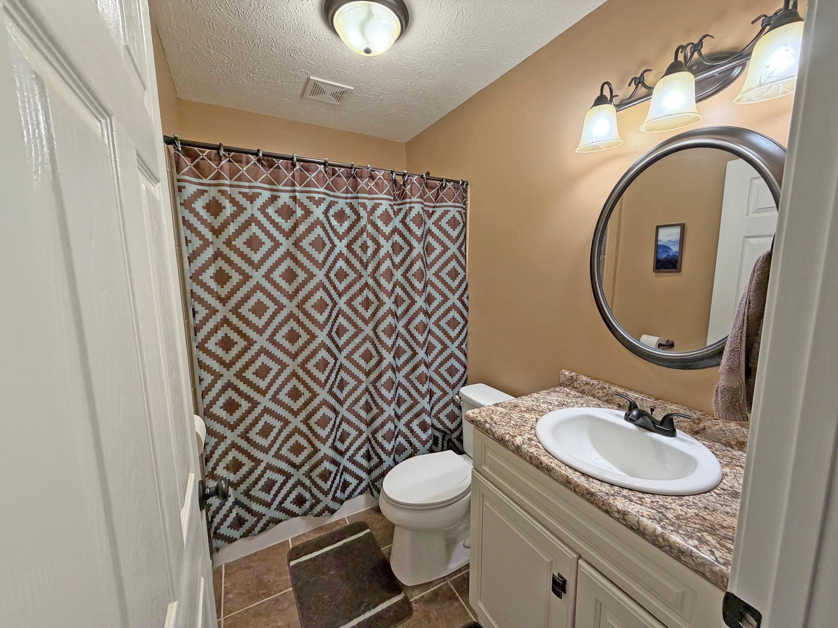 1255 Elm Road Adamsville, TN 38310 - Photo 19 of 32 a bathroom with a granite countertop toilet a sink and a mirror