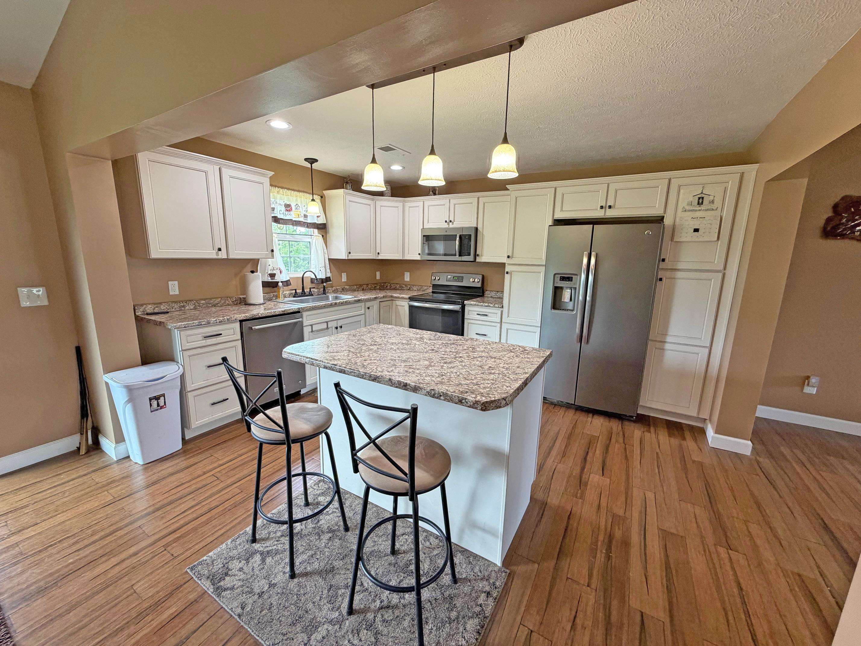 1255 Elm Road Adamsville, TN 38310 - Photo 2 of 32 a kitchen with stainless steel appliances a dining table chairs stove refrigerator and wooden floor