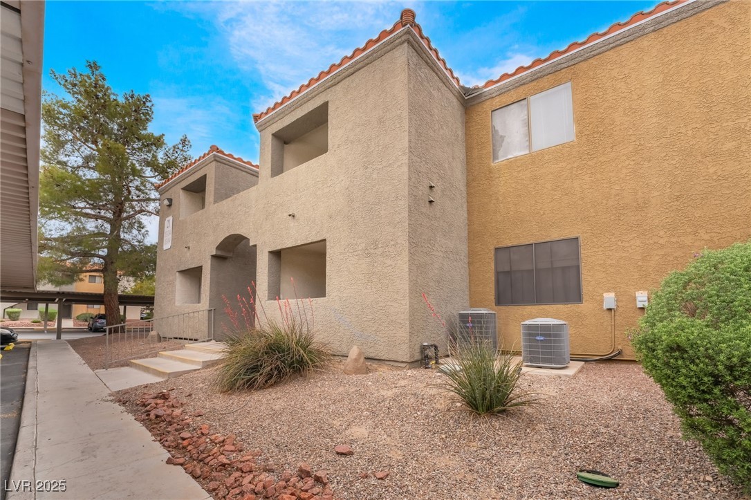 View of side of home featuring a tile roof and stucco siding