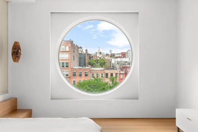 a spacious bedroom with a bed a wall painting and a potted plant