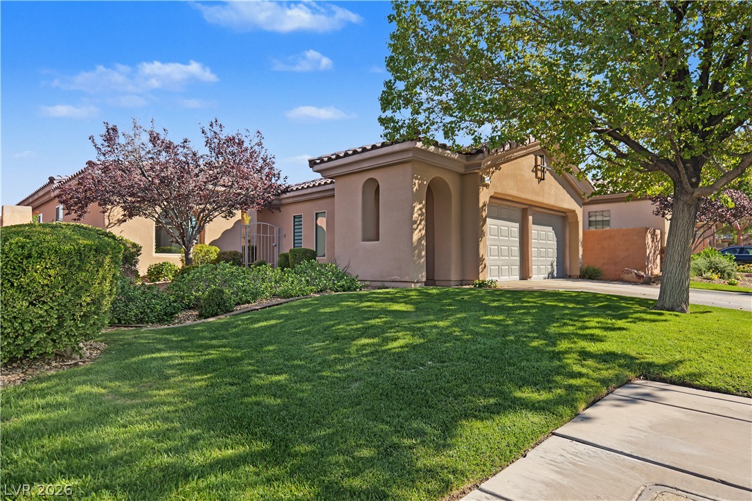 6 Mohansic Road Henderson, NV 89052 - Photo 4 of 38 Mature trees shade a manicured lawn leading toward this southwestern-style stucco home.
